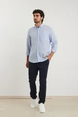 Camisa de manga larga confeccionada en una mezcla de algodón y lino, con cuello abotonado, cierre frontal de botones y un bolsillo en el pecho.