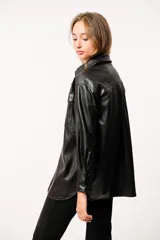 Chaqueta tipo camisa de cuero sintético color negro, con bolsillos frontales y broches metálicos.