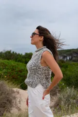 Chaleco tejido a mano en lana merino color gris y blanco, con cuello alto y sin mangas.