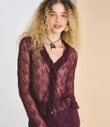 Blusa de encaje transparente color bordó, con mangas largas, escote en V con volados frontales y bajo fruncido.