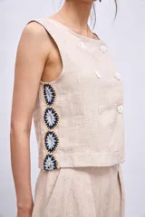 Chaleco celeste con diseño cruzado y doble botonadura, sin mangas y con apliques de encaje en los laterales.