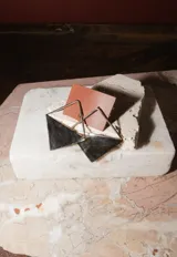 Aros colgantes con diseño geométrico en forma de medio rombo, elaborados en metal con acabado pulido.