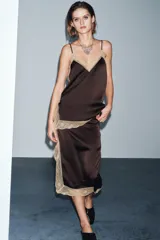 Falda midi de tiro medio, color marrón oscuro, con detalle de encaje color beige a contraste en el bajo y abertura lateral.