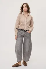 Jean de tiro medio y corte barrel con pierna amplia y ligeramente curva, estilo de cinco bolsillos en denim negro lavado.