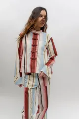 Chaqueta liviana de corte recto con diseño a rayas verticales en tonos marrones, rosados, celestes y amarillos. Cuenta con cuello mao y cierre frontal con alamares.