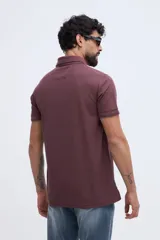Remera polo bordó con textura sutil, cuello y puños acanalados con línea oscura de contraste, cierre frontal parcial de dos botones y logo bordado en el pecho.