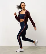 Legging deportiva de tiro alto en color azul marino, con franjas laterales en contraste de color bordó y beige. Confeccionada en microfibra elástica, ofrece un ajuste ceñido y cómodo para actividades físicas.