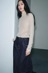 Jeans de tiro alto con pierna ancha, confeccionados en denim azul oscuro. Presentan cinco bolsillos, trabillas en la cintura y un cinturón ajustable del mismo tejido con hebilla metálica. Incluyen pespuntes marcados a tono y cierre frontal con cremallera y botón.