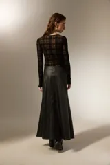 Falda larga de corte evasé confeccionada en cuero sintético negro, con costuras verticales que definen su estructura.