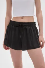 Short negro de poliéster con diseño holgado, cintura elástica con cordón ajustable y bolsillos laterales.