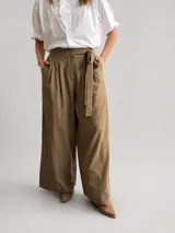 Pantalón palazzo de tiro alto color marrón, confeccionado en lyocell, con cintura elastizada, pinzas delanteras y lazo ajustable.