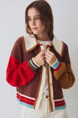 Cardigan de punto con diseño colorblock que combina marrón, rojo y tostado, con mangas abullonadas con textura de ochos, cuello grande en color blanco y cierre frontal con botones.