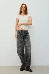 Jeans de tiro bajo y corte holgado de denim negro, con estampado floral en tonos rosados y verdes. Cuenta con diseño de cinco bolsillos y trabillas para cinturón.