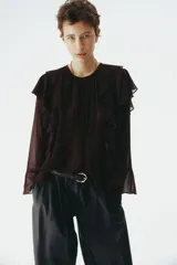 Blusa oversized de tejido transparente color bordó, con escote redondo fruncido, manga larga y ribetes de volados que se extienden desde el frente por los hombros hasta la espalda.