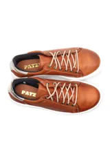 Deportivo de cuero liso color caramelo, con cordones beige y suela blanca. Presenta un detalle metalizado plateado en el talón.