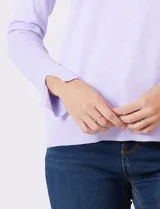 Polera de tejido fino, color rosado, con cuello alto, manga larga y detalle de tajo en los puños.