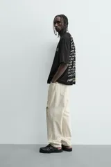 Camiseta negra de corte boxy fit, cuello redondo y manga corta, con estampado frontal en blanco y amarillo que dice "Social Media & Ciao Amore".