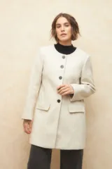 Tapado largo color crema, de paño, con cuello a la base y botones redondos veteados.