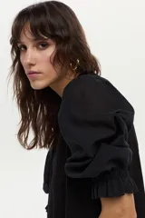 Vestido midi de corte recto color negro, con mangas cortas abullonadas, cuello redondo y detalle de volado en el ruedo.