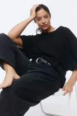 Remera de algodón negro, con cuello redondo ribeteado y mangas cortas de diseño murciélago y corte amplio.