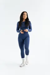 Remera deportiva de manga larga, confeccionada en tejido técnico elástico de color gris oscuro, con diseño ajustado al cuerpo y cuello redondo.