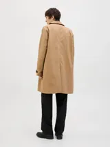 Campera tipo trench coat de corte recto y largo medio, color tostado. Presenta cuello camisero, cierre frontal con botones oscuros y puños ajustables con trabilla y botón.