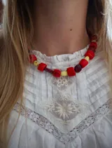 Collar corto compuesto por cuentas de formas irregulares en tonos rojo, amarillo y marrón.