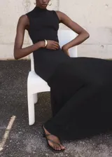 Vestido largo negro de punto fino, con cuello perkins y diseño sin mangas. Presenta un diseño entallado en la parte superior y falda evasé combinada de lyocell.