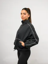 Campera deportiva Umbro de nylon color negro, con cuello alto, cierre frontal y detalles de líneas blancas en contraste. Presenta bolsillos laterales y puños elásticos.