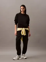 Buzo Calvin Klein de felpa francesa color negro, de corte holgado y diseño con cuello redondo. Cuenta con mangas largas, puños y dobladillo acanalados, y lleva el logo retro de la marca bordado discretamente en el pecho.