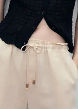 Short de lino y viscosa color beige, de diseño recto y corte corto, con cintura elástica y cordón ajustable con cuentas de madera.