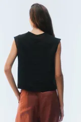 Top negro de lino con calce recto y ligeramente holgado, cuello redondo alto, hombros estructurados y sisa pronunciada.