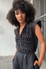 Mono negro de lino y algodón texturizado con plisados de pespuntes de color en contraste. Tiene lazo en la cintura y fuelle en la espalda.