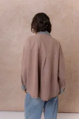 Camisa de denim color verde menta con calce relajado, cuello clásico, cierre frontal con broches metálicos, mangas largas y bolsillo aplicado en el pecho, con detalles en tono gris azulado a contraste en cuello, cartera, bolsillo y puños.