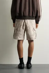 Bermuda cargo color negro de corte relaxed fit, confeccionada en tejido de algodón con elasticidad y efecto lavado. Cuenta con cintura elástica ajustable con cordón, bolsillos frontales y bolsillos laterales tipo cargo con solapa en las perneras.