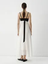 Vestido midi con breteles finos, cuerpo superior negro y falda blanca.