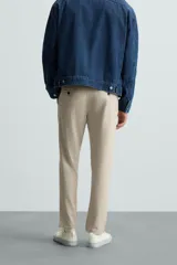 Pantalón chino de corte slim fit, confeccionado en tejido elástico. Presenta bolsillos frontales, bolsillos traseros de vivo con botón y cierre frontal con cremallera y botón.