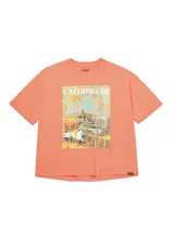 Remera de corte boxy color naranja con estampa frontal que ilustra un tractor en un campo otoñal y logo de la marca. Presenta cuello redondo, mangas cortas y etiqueta pequeña con logo en el dobladillo inferior.