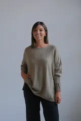 Sweater de punto con acabado brillante en tono verde oliva, de corte holgado y diseño con costuras verticales decorativas. Presenta cuello redondo y mangas largas con puños ajustados.