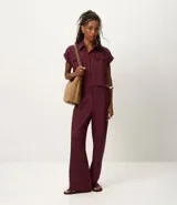 Pantalón de corte recto color bordó, confeccionado en tejido Orly con fondo melange. Presenta cintura con elástico en la parte posterior y cierre tradicional frontal.