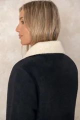 Montgomery de lana color negro con cuello de punto en color crema, cierre frontal con alamares y bolsillos con solapa.