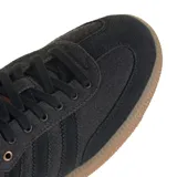 Championes adidas Samba OG de diseño clásico, con cuerpo en color negro, detalles en cuero marrón en el talón y lengüeta, y suela de goma color caramelo.