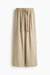 Pantalón color beige de corte amplio, con cintura elástica y lazo para atar. Confeccionado en sarga de mezcla de modal, con bolsillos laterales y un bolsillo decorativo atrás.