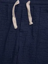 Pantalón azul marino de algodón con textura, cintura elastizada con cordón, bolsillos laterales y trasero.