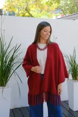 Saco abierto tipo capa en color bordó, confeccionado en tejido de punto suave, con mangas amplias y detalle de flecos en el ruedo.