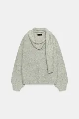 Jersey de punto de corte holgado en color gris jaspeado, con escote en pico y bufanda integrada del mismo tejido. Presenta mangas largas con puños ajustados.