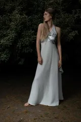 Vestido largo con pechera de cuero metalizado y falda tejida con hilo de lurex brillante. Presenta un diseño de cuello halter y corte fluido.