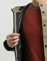 Gabardina con capucha de corte recto y largo medio. Cuenta con cierre frontal engomado, cartera con botones a presión, bolsillos laterales y tejido repelente al agua y al viento.