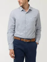 Camisa de manga larga con diseño de rayas verticales en tonos gris y blanco. Presenta cuello italiano, cierre frontal con botones y un bolsillo en el pecho con el logo de la marca bordado.