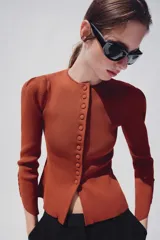 Chaqueta de punto color óxido, con cuello redondo, manga larga abullonada y cierre frontal con botones.